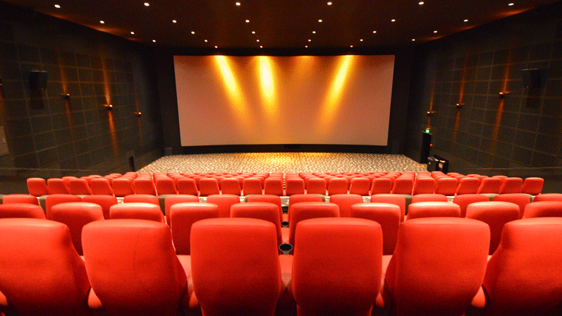 En lille biograf uden mennesker. Biografsæderne er røde og lyset i rummet er gult