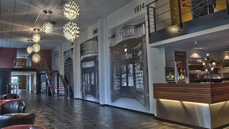 Et Loungeområde i en biograf med store lysekroner, læderstole. malerier på væggene og en moderne bar